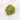 A small mound of bright green powder, likely matcha or tea powder, scattered on a white marble surface.